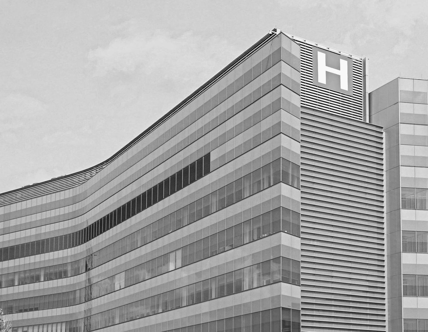 A hospital building with a large H sign